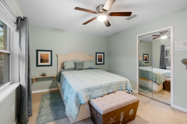 tiled bedroom with ceiling fan and a closet