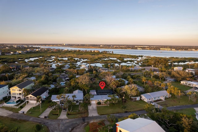 aerial view at dusk featuring a water view