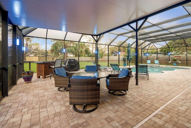 patio terrace at dusk with exterior bar, a swimming pool with hot tub, a lanai, and a grill