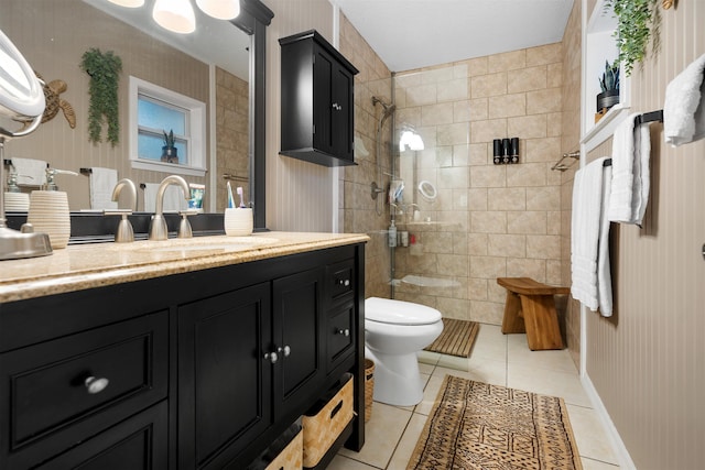 bathroom with tile patterned floors, vanity, tiled shower, and toilet