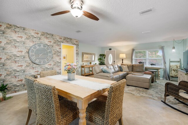 tiled dining area featuring ceiling fan and a textured ceiling