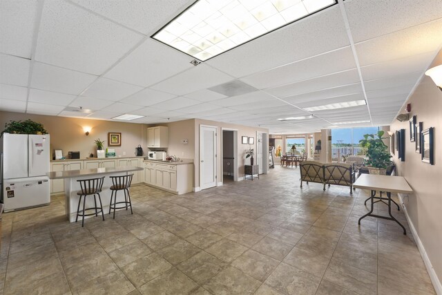 155 Marine St Unit 202, Saint Augustine, FL 32084 - kitchen featuring freestanding refrigerator, a paneled ceiling, a kitchen island, a breakfast bar area, and light countertops