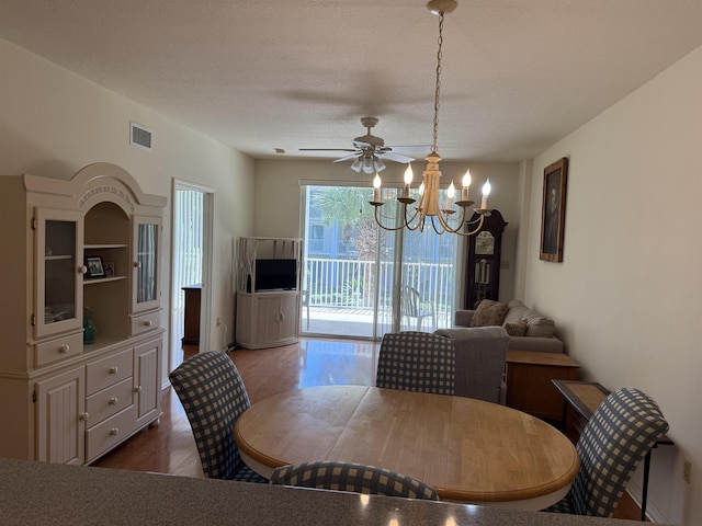 dining room with ceiling fan with notable chandelier, visible vents, wood finished floors, and a textured ceiling