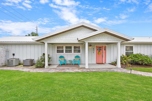 view of front of home featuring cooling unit, board and batten siding, and a front yard