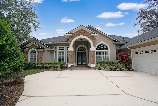 view of front facade featuring concrete driveway, french doors, an attached garage, and stucco siding