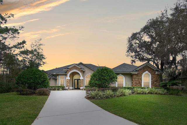 ranch-style house with driveway, a front lawn, and stucco siding