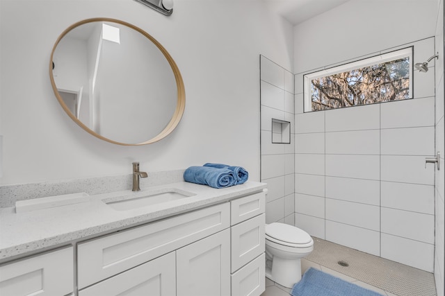 bathroom with a tile shower, tile patterned floors, vanity, and toilet