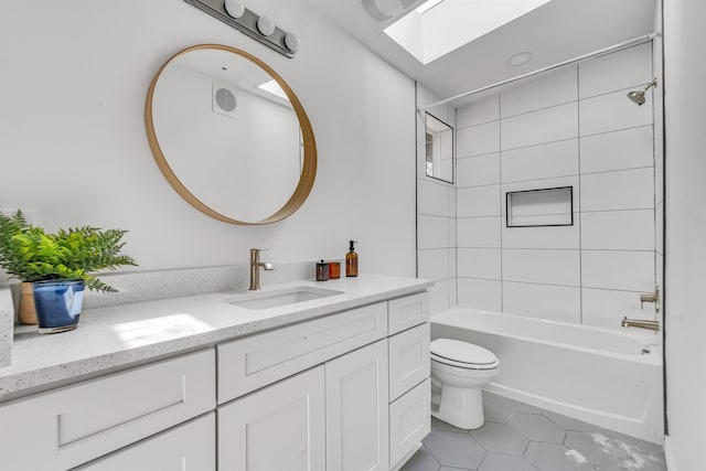 full bathroom with a skylight, tiled shower / bath combo, tile patterned flooring, toilet, and vanity