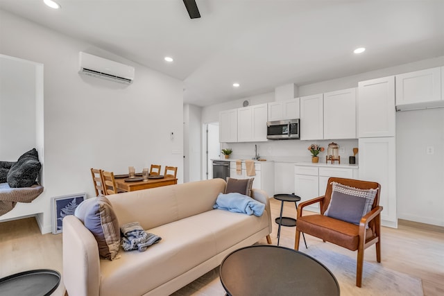 living room featuring light wood-type flooring, sink, and a wall unit AC