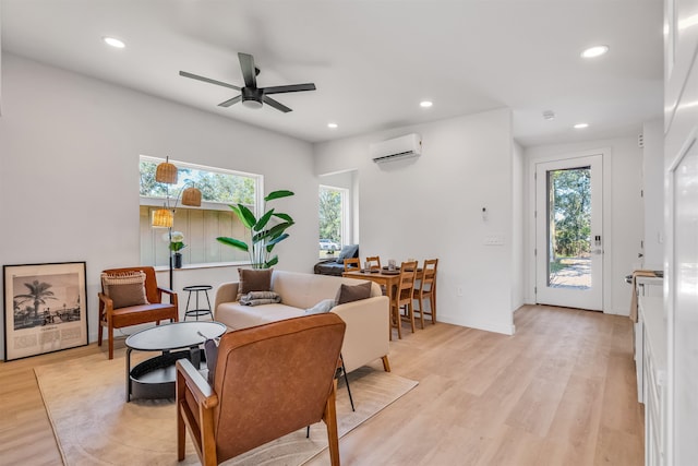 living room with ceiling fan, an AC wall unit, and light hardwood / wood-style flooring