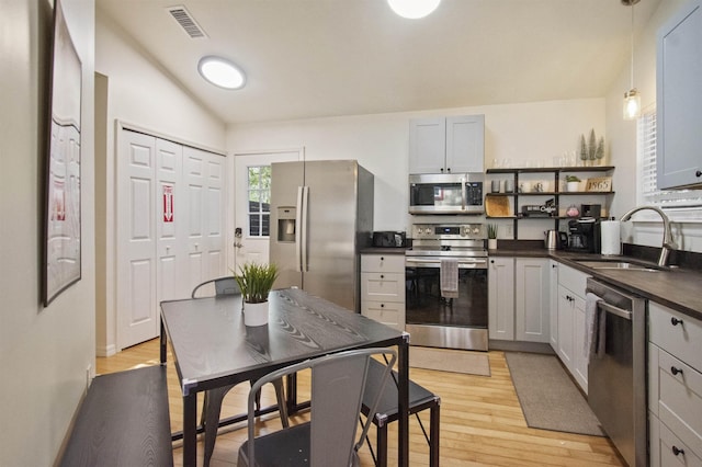 5 Nesbit Ave, Saint Augustine, FL 32084 - kitchen featuring stainless steel appliances, open shelves, dark countertops, light wood-type flooring, and lofted ceiling