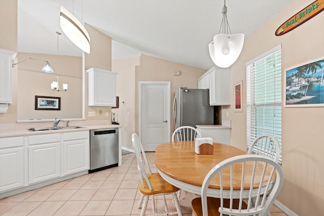 kitchen with lofted ceiling, white cabinets, sink, hanging light fixtures, and appliances with stainless steel finishes