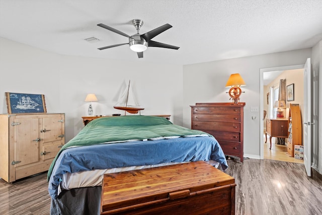 bedroom with hardwood / wood-style floors, a textured ceiling, and ceiling fan