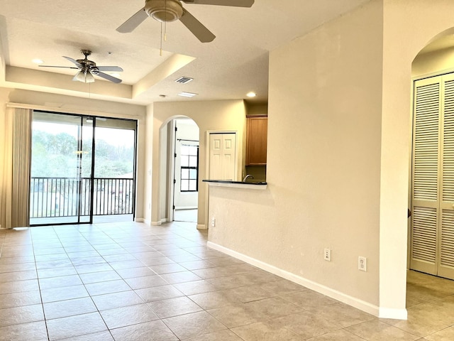 spare room featuring ceiling fan, light tile patterned flooring, and a raised ceiling