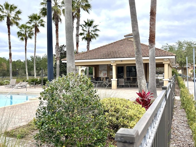 rear view of property with a community pool and a patio