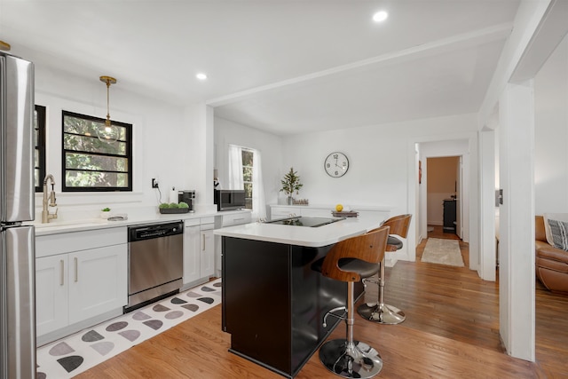 kitchen with a center island, stainless steel appliances, light hardwood / wood-style flooring, pendant lighting, and white cabinets