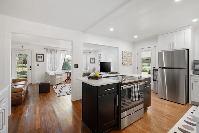 kitchen with white cabinets, appliances with stainless steel finishes, a kitchen island, and plenty of natural light