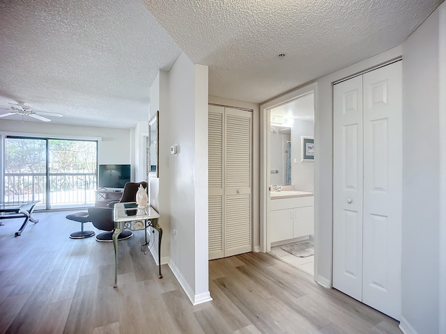 corridor featuring sink, light hardwood / wood-style floors, and a textured ceiling