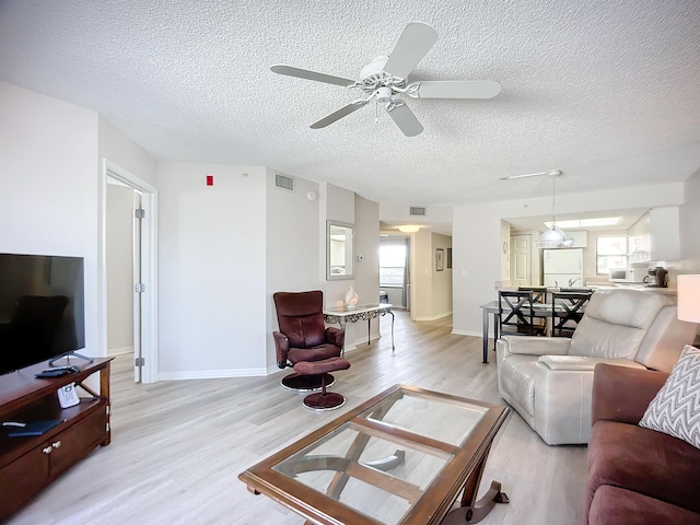 living room featuring a textured ceiling, light hardwood / wood-style floors, and ceiling fan