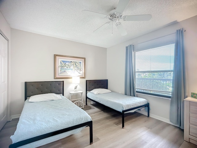 bedroom featuring a textured ceiling, light wood-type flooring, and ceiling fan