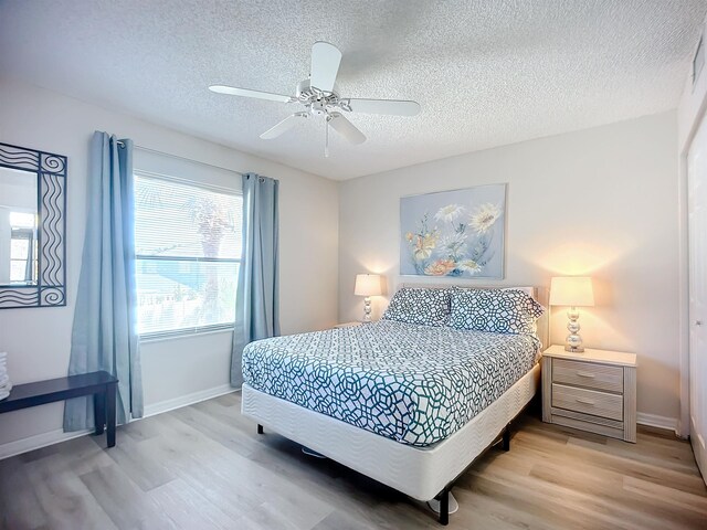 bedroom featuring ceiling fan, light hardwood / wood-style floors, and a textured ceiling