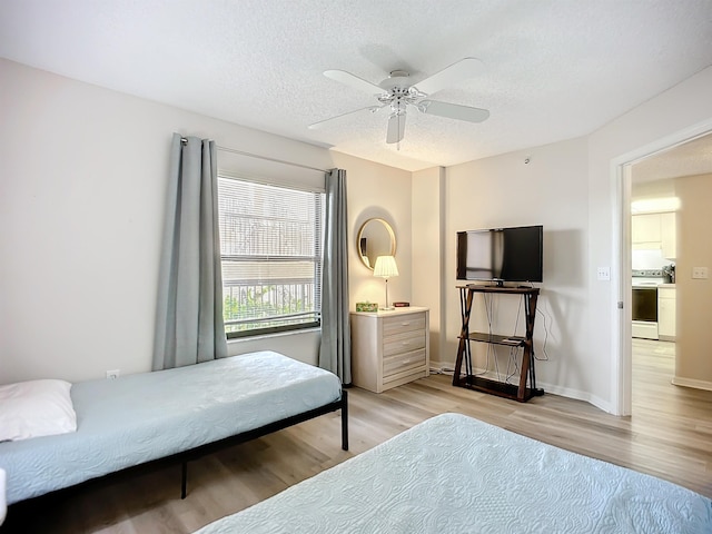 bedroom featuring ceiling fan, light wood-type flooring, and a textured ceiling