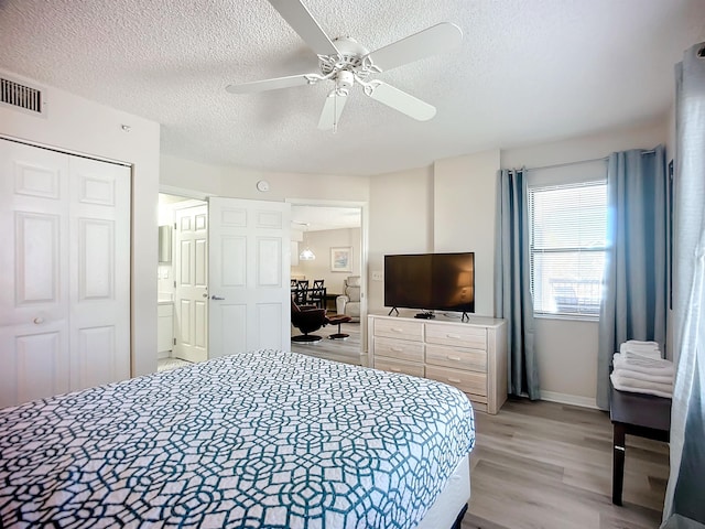 bedroom featuring ceiling fan, light wood-type flooring, a textured ceiling, and a closet