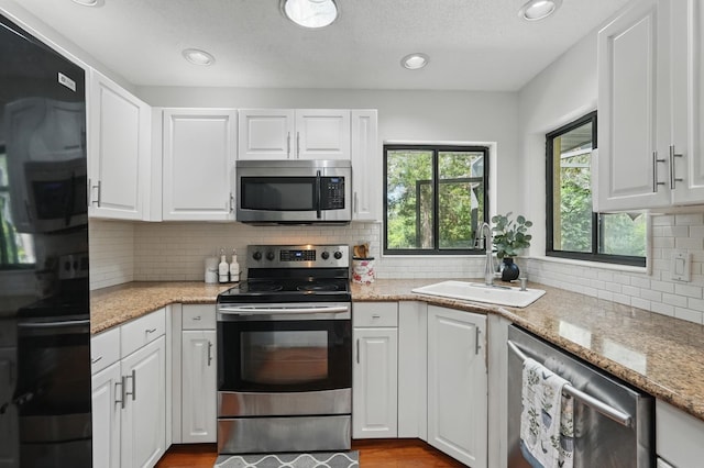 131 Boulder Rock Dr, Palm Coast, FL 32137 - kitchen featuring stainless steel appliances, white cabinets, tasteful backsplash, light stone countertops, and a textured ceiling