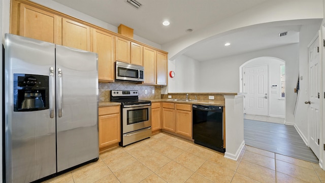 kitchen featuring kitchen peninsula, light brown cabinetry, stainless steel appliances, sink, and light tile patterned floors