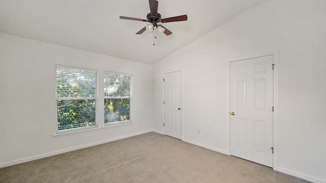 unfurnished bedroom featuring multiple windows, ceiling fan, light colored carpet, and lofted ceiling