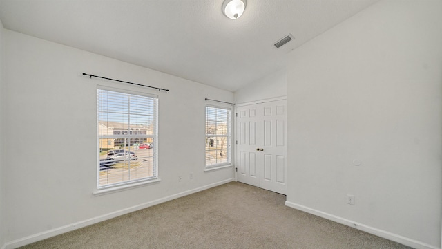 unfurnished room with lofted ceiling and light carpet