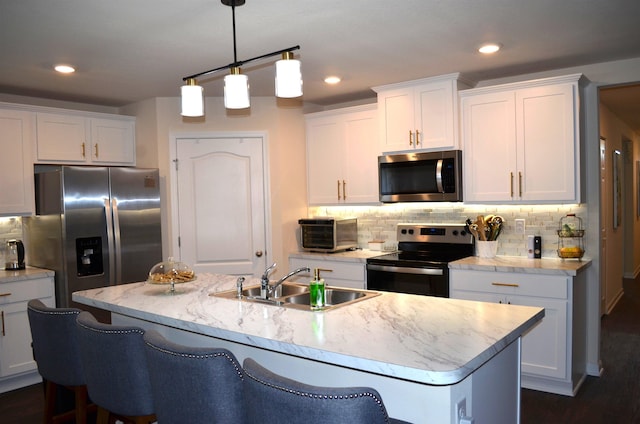 35 Putter Dr, Palm Coast, FL 32164 - kitchen with stainless steel appliances, white cabinets, backsplash, a center island with sink, and decorative light fixtures