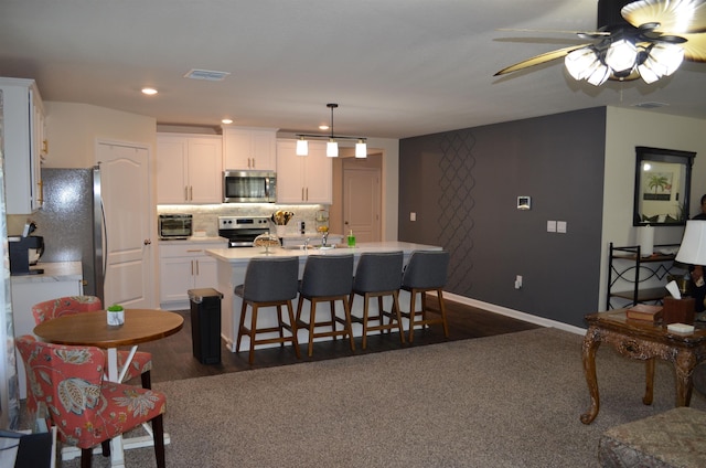 35 Putter Dr, Palm Coast, FL 32164 - kitchen with appliances with stainless steel finishes, white cabinets, light countertops, a kitchen island with sink, and recessed lighting