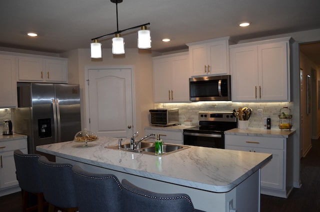 35 Putter Dr, Palm Coast, FL 32164 - kitchen with stainless steel appliances, white cabinetry, tasteful backsplash, an island with sink, and decorative light fixtures