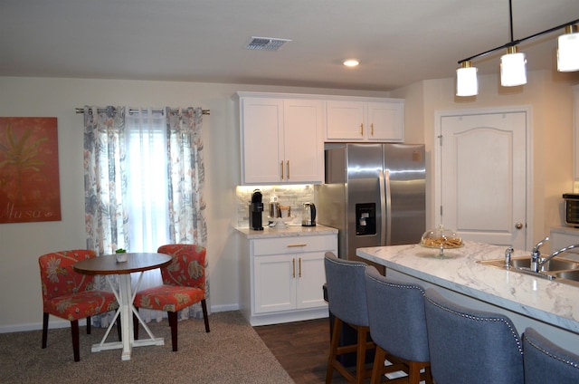 35 Putter Dr, Palm Coast, FL 32164 - kitchen with stainless steel fridge with ice dispenser, white cabinets, decorative light fixtures, a kitchen bar, and decorative backsplash