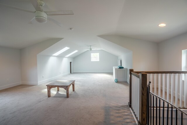 bonus room featuring vaulted ceiling with skylight, ceiling fan, and light colored carpet