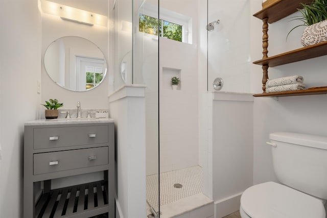 bathroom featuring a tile shower, vanity, and toilet