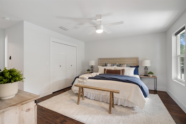 bedroom with a closet, dark hardwood / wood-style floors, and ceiling fan