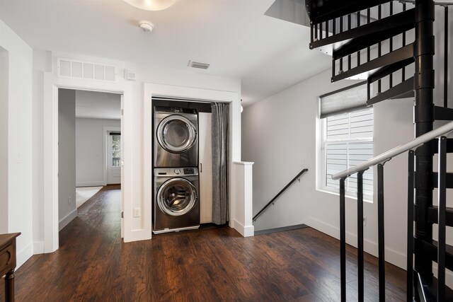 laundry room with dark hardwood / wood-style flooring and stacked washer and dryer