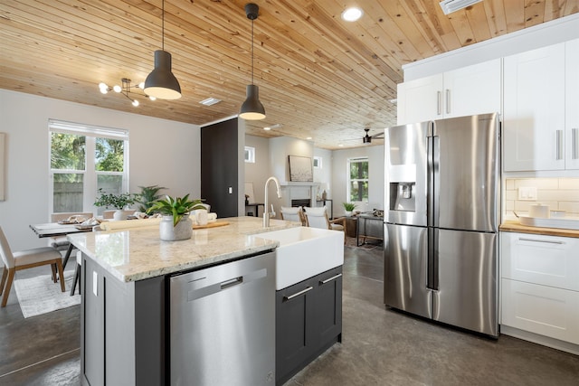 kitchen featuring stainless steel appliances, sink, a center island with sink, white cabinetry, and hanging light fixtures