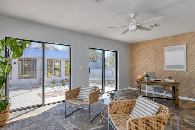 living room featuring ceiling fan and wooden walls