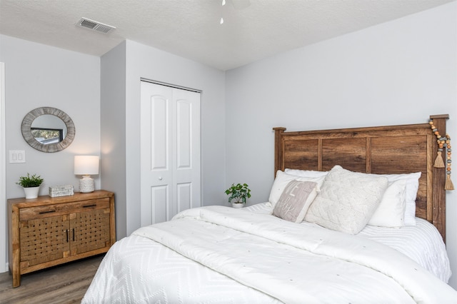 bedroom featuring ceiling fan, a closet, wood-type flooring, and a textured ceiling