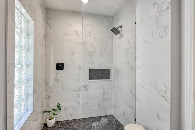 bathroom with a tile shower and a healthy amount of sunlight