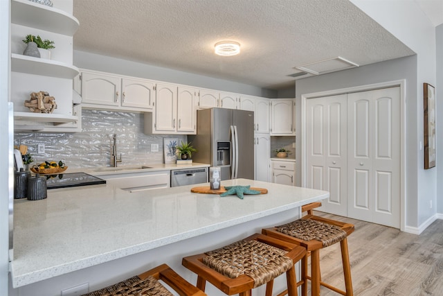 kitchen with a breakfast bar area, sink, light wood-type flooring, and appliances with stainless steel finishes