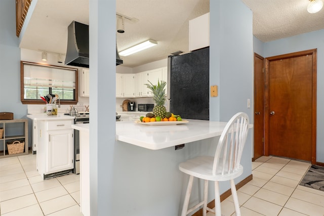 kitchen with stainless steel fridge, a textured ceiling, white cabinetry, and a kitchen breakfast bar