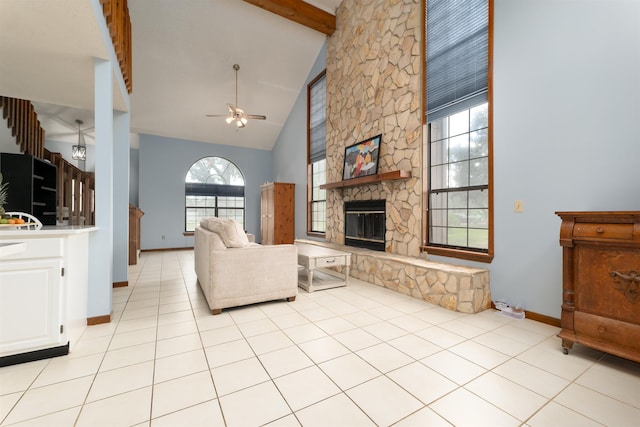 unfurnished living room featuring ceiling fan, beam ceiling, high vaulted ceiling, a stone fireplace, and light tile patterned flooring