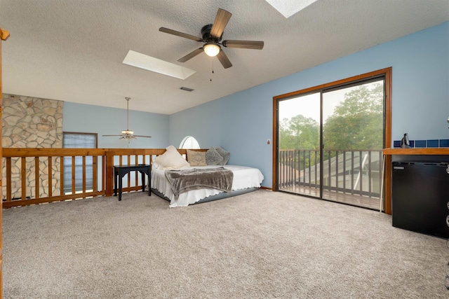 bedroom with carpet, black fridge, a skylight, access to exterior, and a textured ceiling