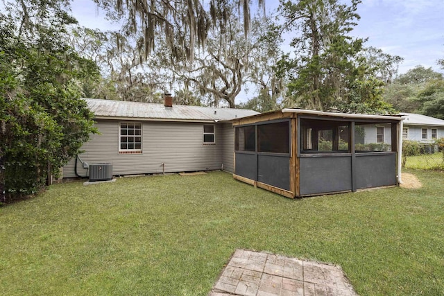 rear view of house featuring a sunroom, a yard, and central air condition unit