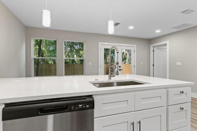 kitchen with stainless steel dishwasher, white cabinetry, visible vents, light countertops, and a sink
