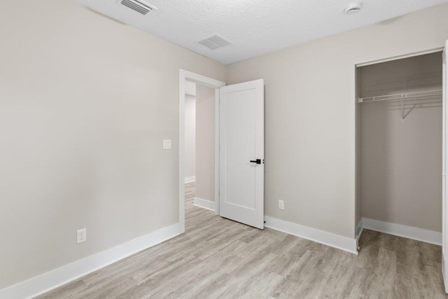 unfurnished bedroom with visible vents, baseboards, a closet, and light wood-style floors